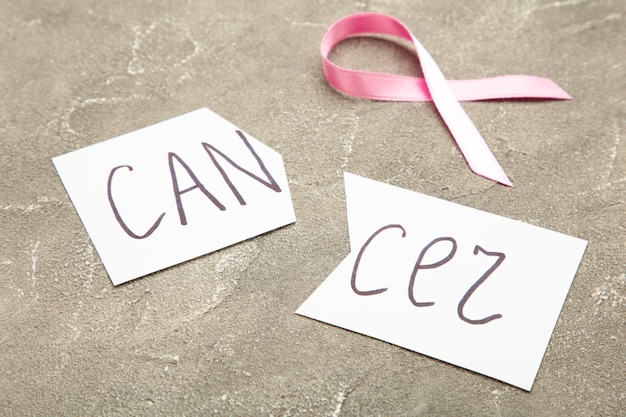 Photo ciseaux coupant un morceau de papier avec le mot cancer avec ruban rose