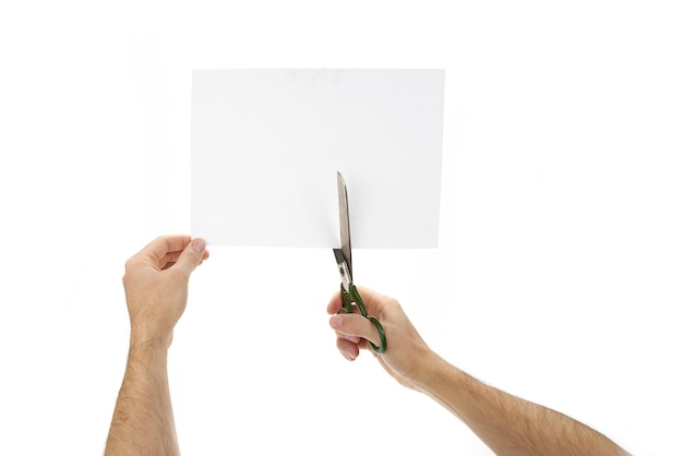 Photo des ciseaux dans les mains coupent du papier sur un fond blanc