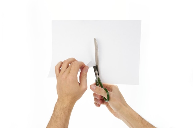 Photo des ciseaux dans les mains coupent du papier sur un fond blanc