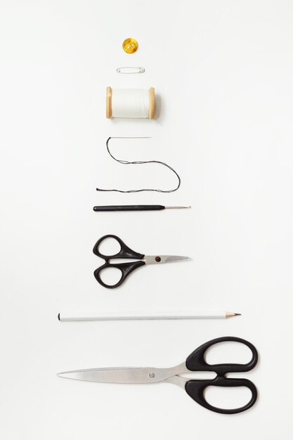 Photo des ciseaux et des fournitures de couture sur un bureau blanc des outils à coudre et à tricoter sur un fond blanc concept d'aiguillage vue supérieure sur blanc