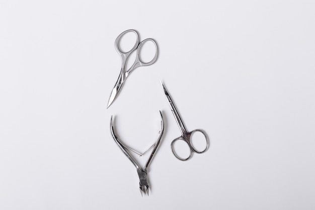 Ciseaux à manucure et forceps pour manucure sur une table blanche