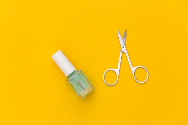 Ciseaux de vernis à ongles et de manucure sur fond jaune. Notion de beauté. Vue de dessus