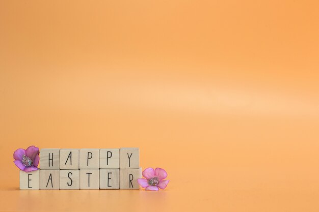 Citation de joyeuses pâques sur des cubes en bois avec des fleurs de printemps violettes