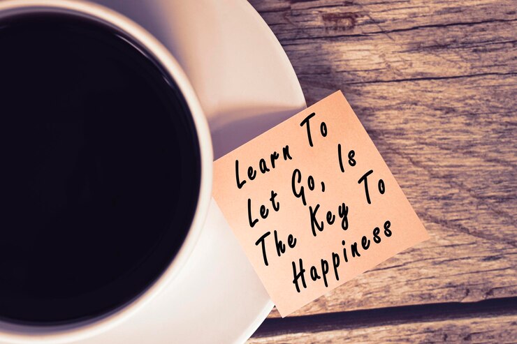 Photo citation motivante et inspirante sur des notes avec une tasse de café apprenez à lâcher prise est la clé du bonheur