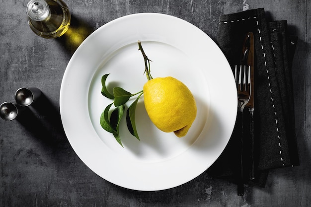 Citron sur une assiette table vaisselle couverts sur fond sombre