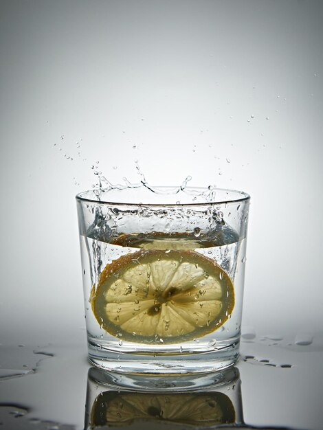 Citron éclaboussant dans un verre d'eau