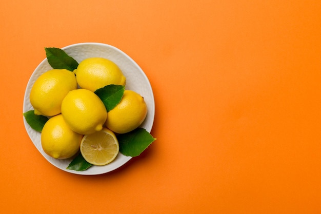 Citron frais coupé et citrons entiers sur une assiette ronde sur fond coloré Ingrédients de nourriture et de boisson préparant une alimentation saine thème vue de dessus avec espace de copie