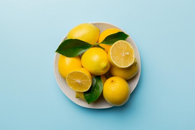 Citron frais coupé et citrons entiers sur une assiette ronde sur fond coloré Ingrédients de nourriture et de boisson préparant une alimentation saine thème vue de dessus avec espace de copie