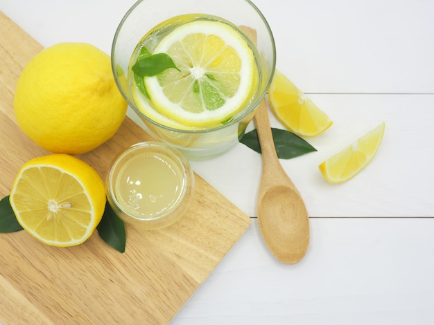 Citron frais dans l&#39;eau, limonade et citron tranche sur fond de bois blanc