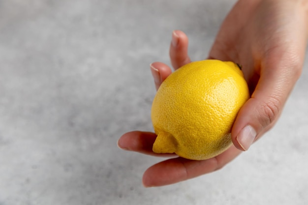 Un citron à la main et sur fond gris