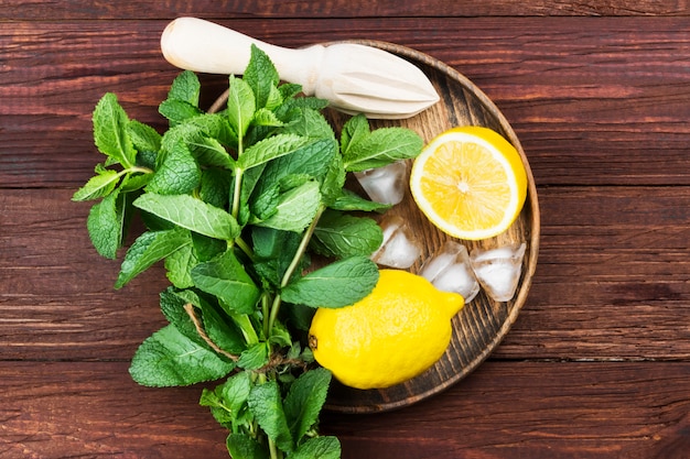 citron, menthe, glace dans un plateau en bois sur un fond en bois