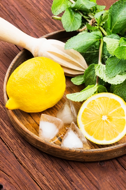 Photo citron, menthe, glace dans un plateau en bois sur un fond en bois