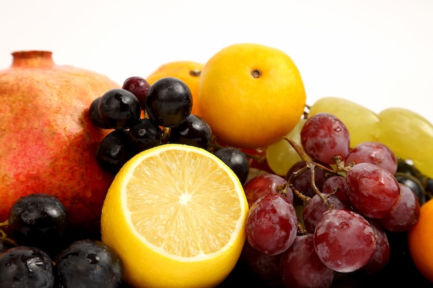 Citron, raisins et grenade sur une surface blanche