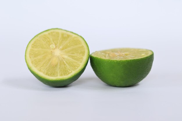 Photo un citron vert coupé en deux et demi sur un fond blanc