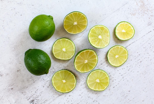 Citron vert entier et agrumes tranchés sur une pierre blanche comme un bureau, vue d'en haut