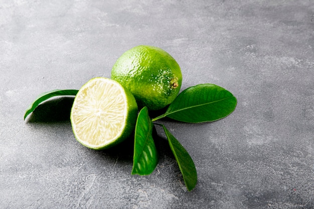 Citron vert mûr entier et coupé en deux avec des feuilles sur la table