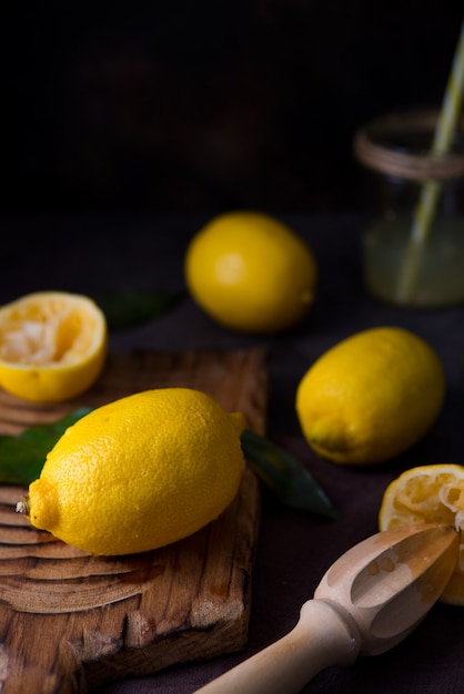 Citrons biologiques juteux mûrs sur une planche de bois, fond sombre, gros plan