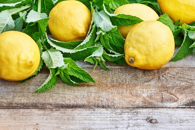 Citrons avec des feuilles de menthe sur table en bois