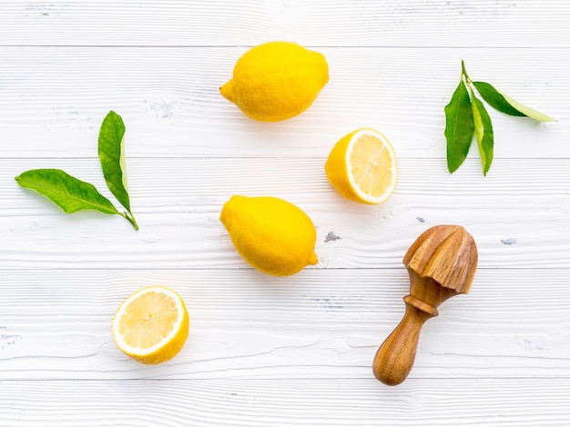 Citrons frais et citrons feuilles sur un fond en bois blanc.