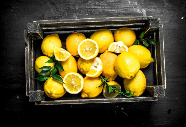 Citrons frais dans une boîte en bois. Sur le tableau noir.