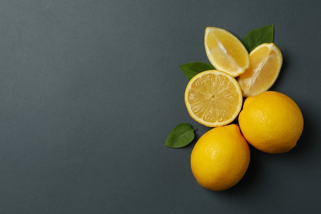 Citrons frais avec des feuilles sur une surface noire. Fruits mûrs