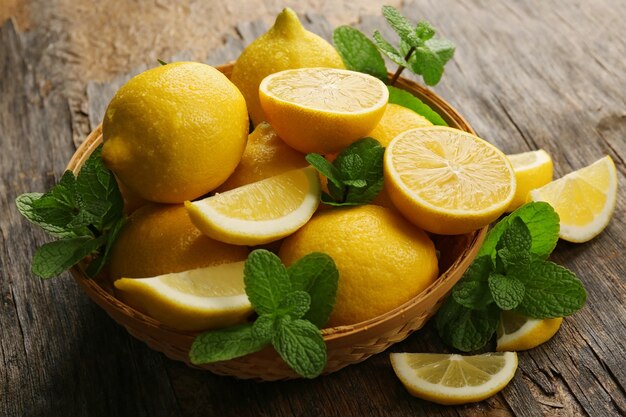 Citrons frais avec des feuilles vertes dans un bol sur fond de bois