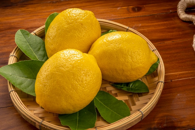 Photo citrons jaunes frais avec des feuilles sur un panier en bambou.