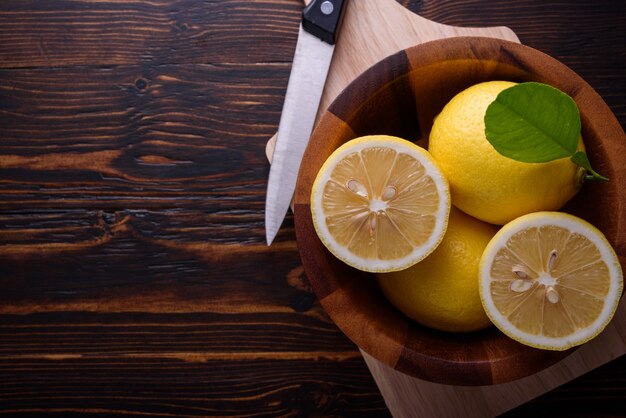 Citrons mûrs frais et couteau sur la table en bois. Vue de dessus avec espace copie