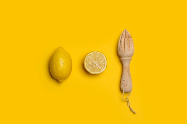 Citrons et un presse-agrumes en bois sur fond jaune en vue de dessus