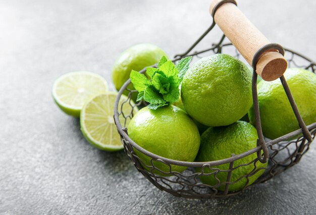 Des citrons verts avec des feuilles de menthe fraîches sur un fond en béton de panier