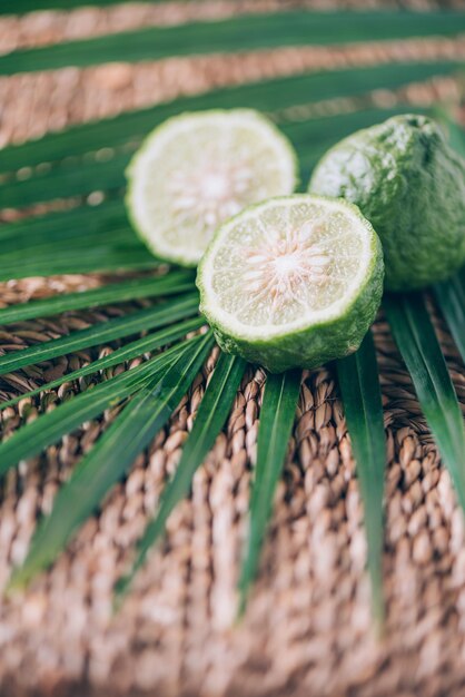 Citrons verts mûrs frais sur des feuilles de palmier sur fond de rotin Espace de copie Acca sellowiana Bannière de conception créative Heure d'été Voyage tropical fruits exotiques Concept végétalien et végétarien