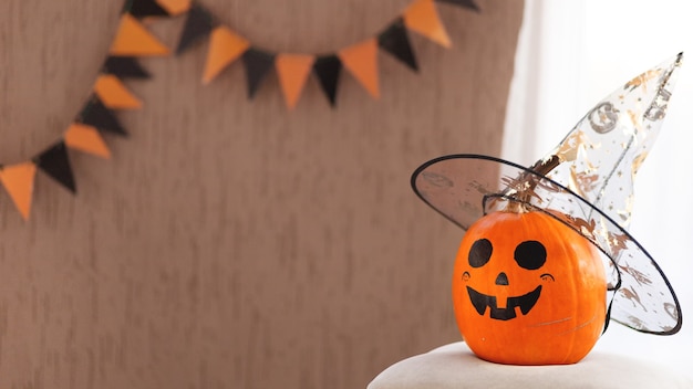 Une citrouille amusante dans un chapeau pour halloween est située sur le bon copyspace