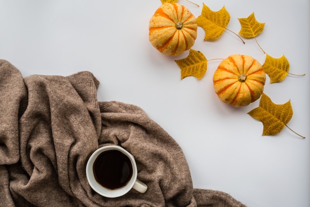 Citrouille d'automne, tasse à café noire, pull et feuilles d'automne