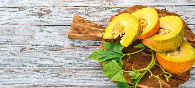 Citrouille coupée en tranches sur une planche de bois Légumes frais Sur une table en bois blanc Espace libre pour le texte Vue de dessus