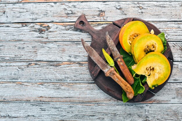 Citrouille coupée en tranches sur une planche de bois Légumes frais Sur une table en bois blanc Espace libre pour le texte Vue de dessus