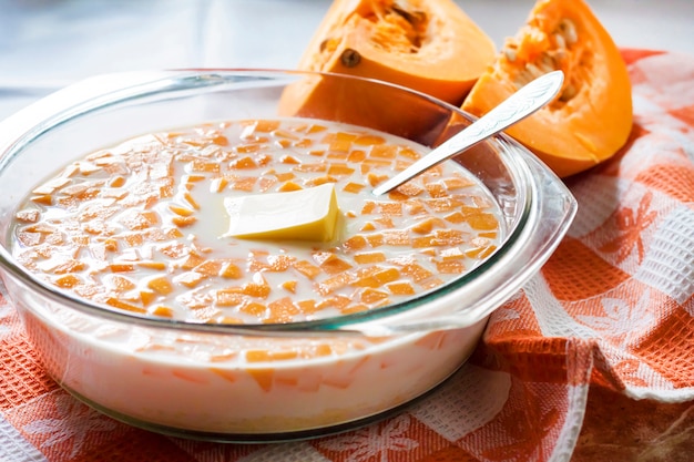 Citrouille crue, lait et beurre dans une casserole en verre dans le processus de cuisson de la bouillie de citrouille avec augmentation