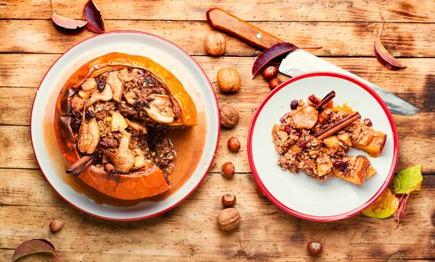 Citrouille farcie au granola et aux fruits secs sur une vieille table en bois