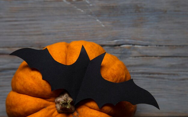 Citrouille d'Halloween et chauve-souris vampire noire sur un fond en bois