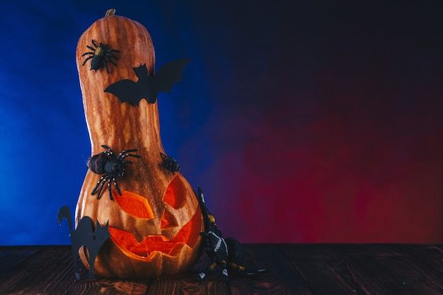 Citrouille d'Halloween dans une toile d'araignée avec des bonbons et un éclairage sombre. Trick or Treat concept sur fond bleu et rouge