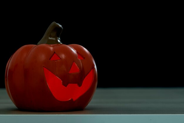 Citrouille d'Halloween Jack O lanterne sur une table en bois devant un fond sombre effrayant texturé pour la conception de bannières