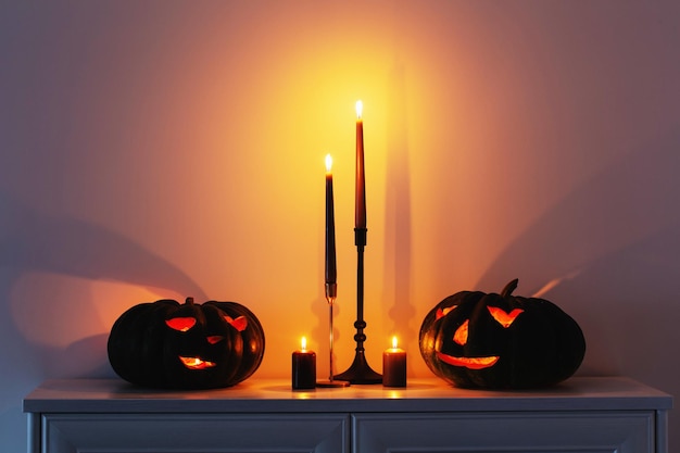 Citrouille d'halloween noire avec des bougies allumées dans un intérieur blanc