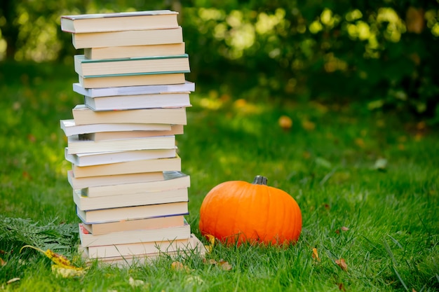 Citrouille et livres sont sur une herbe verte dans un jardin