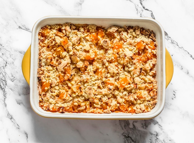 Citrouille et pommes crumble dans un plat allant au four sur fond clair vue de dessus Délicieux dessert de saison