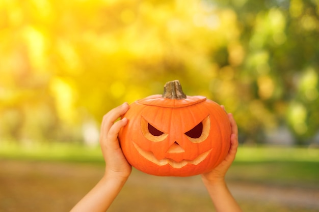 Une citrouille avec un sinistre sourire de lanterne jacko dans les mains à l'Halloween