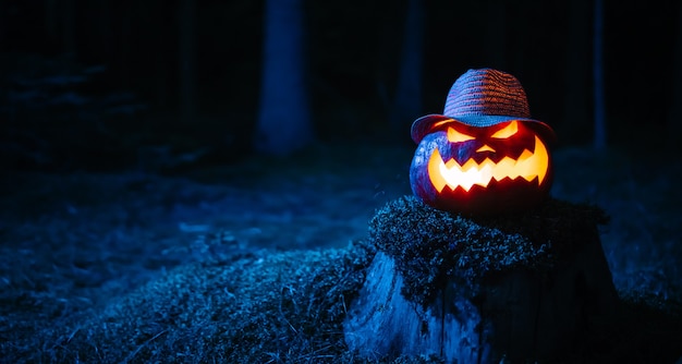 Citrouille avec un visage sculpté terrifiant pour Halloween avec un rétro-éclairage sur fond de glo...