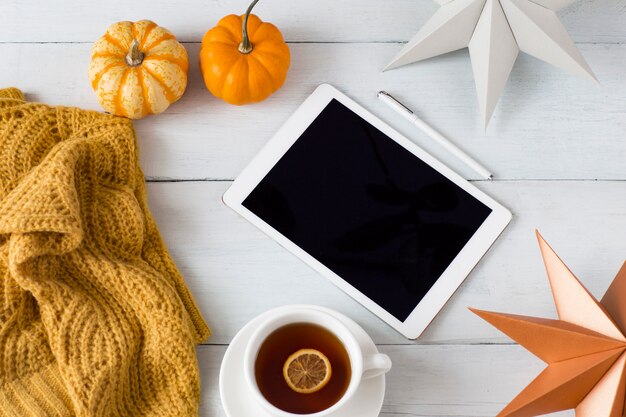 citrouilles blanches et orange, une couverture orange tricotée, décor, feuilles d&#39;automne, un stylo et une tablette et tasse de thé