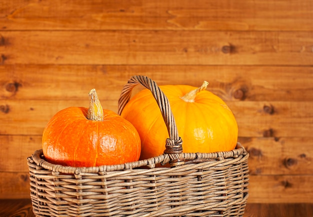 Citrouilles dans un panier en osier gros plan sur un fond de bois