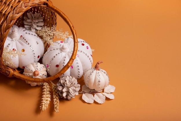 Citrouilles décoratives blanches faites à la main avec des pierres brillantes et des pommes de pin dans le panier sur fond coloré concept de récolte d'automne