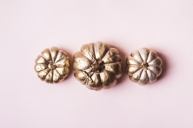 Citrouilles dorées sur rose pastel.