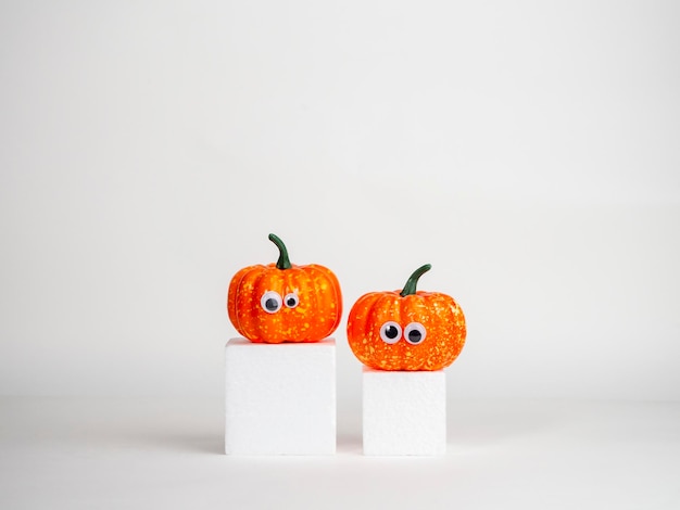 Citrouilles drôles avec des yeux sur un cube blanc Concept d'Halloween Idée créative